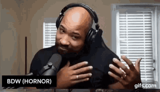 a man wearing headphones is sitting in front of a microphone .