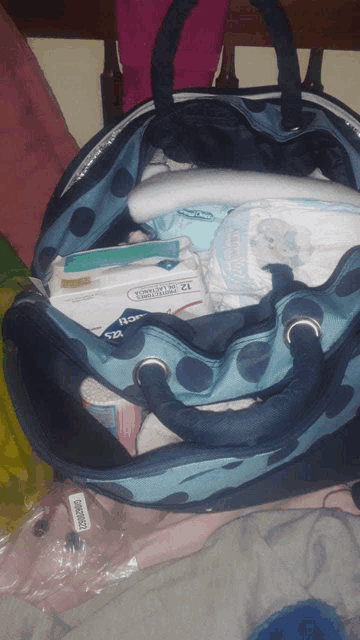 a blue polka dot bag filled with diapers wipes and a box of kleenex