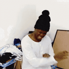 a man wearing a beanie and a white shirt is standing in a room
