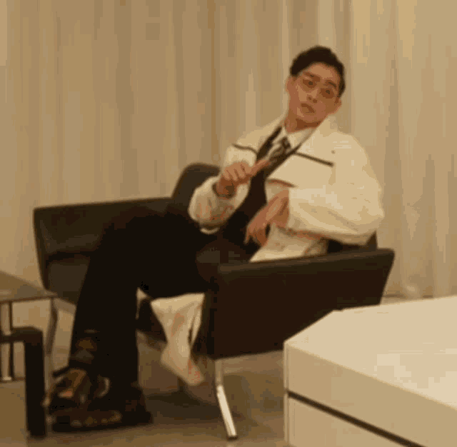 a man in a white coat sits in a chair