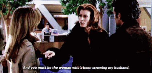 a woman in a black coat is talking to a man and a woman in a brown coat