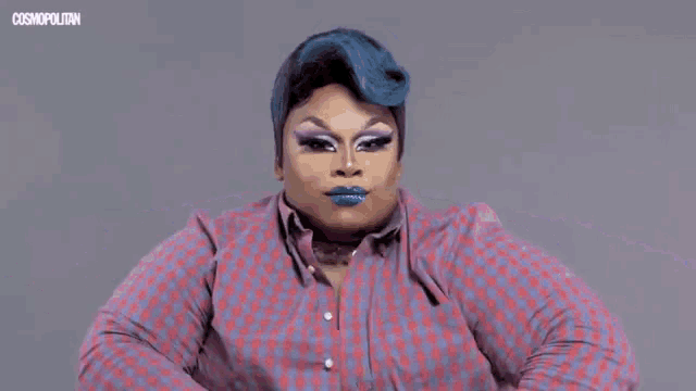 a drag queen is wearing a plaid jacket and a white top .