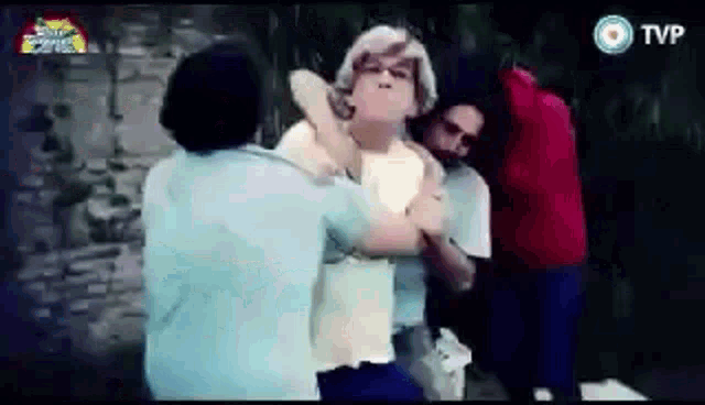 a group of people are standing next to each other and one of them is holding another man 's neck .