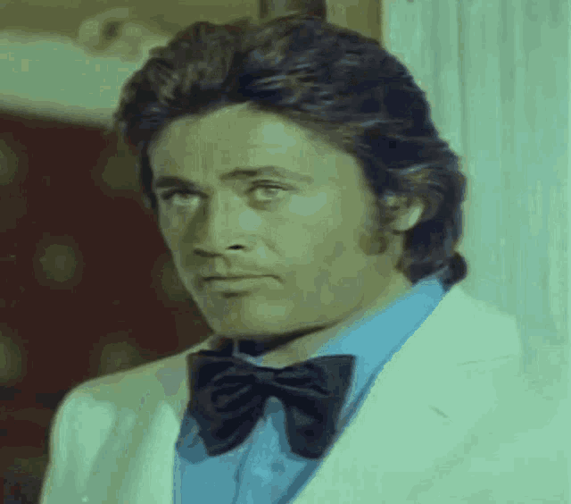 a man wearing a white jacket and a blue shirt with a black bow tie