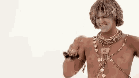 a shirtless man is wearing a gold necklace and bracelets .