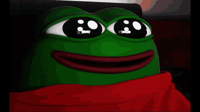 a green frog is wearing a red scarf around his neck