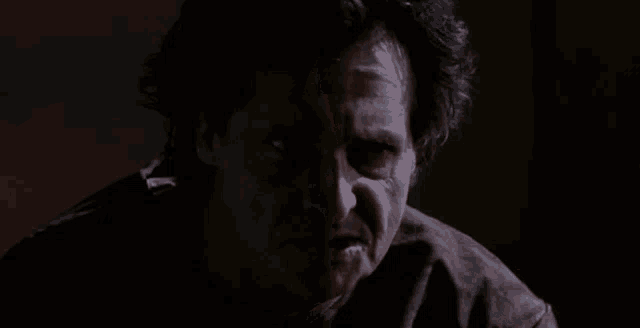 a close up of a man 's face in the dark with his eyes closed .