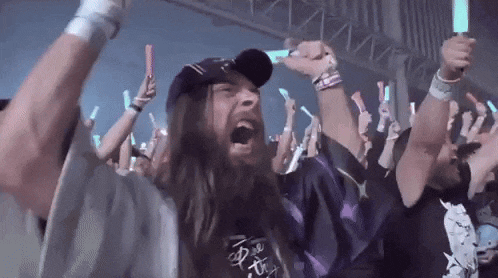 a man with a beard is screaming in a crowd at a concert