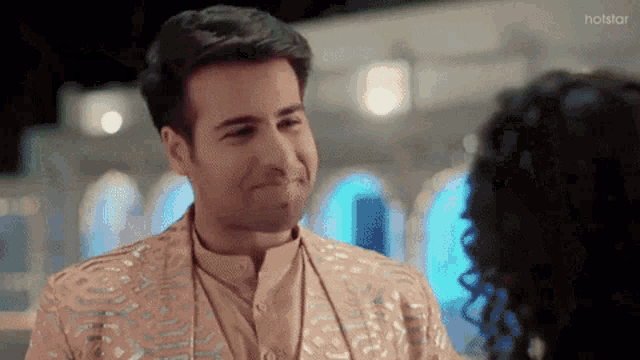 a man in a gold suit is looking at a woman in a dark room .