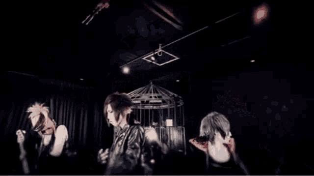 a man in a leather jacket is holding a guitar in a dark room .