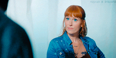 a woman with red hair and blue eyes wearing a denim jacket
