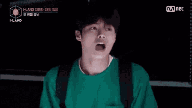 a man in a green sweater is making a funny face .
