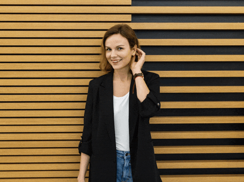 a woman stands in front of a wooden wall