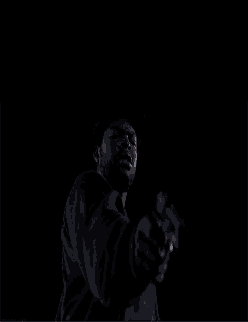 a man is pointing a gun at the camera in a dark room