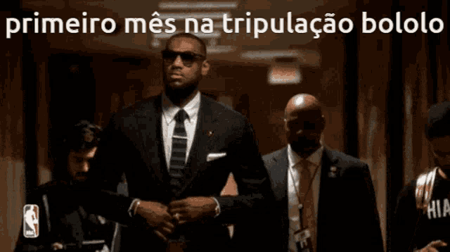 a man in a suit and tie is standing in a hallway with a caption that says primeiro mes na tripulacao bololo