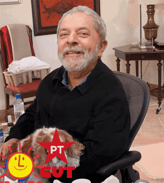 a man sitting in a chair holding a small dog with a red star that says pt cut on it
