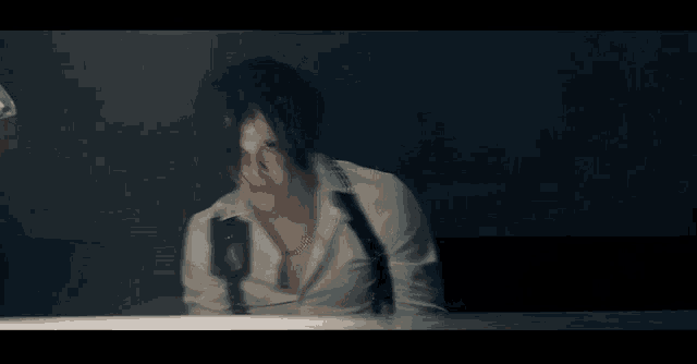 a man is sitting at a table with handcuffs on his wrists .