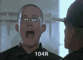 a man wearing glasses is screaming at another man in a military uniform .