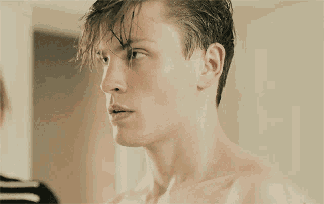 a close up of a man 's face with a striped shirt in the background