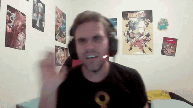 a man wearing headphones and a naruto poster on the wall behind him