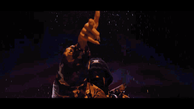 a man in a camouflage jacket stands in the rain