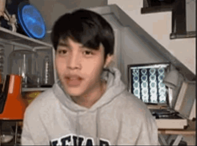 a young man wearing a grey hoodie with the word atlanta on it looks at the camera .