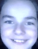 a close up of a child 's face with a blue background and a smile .