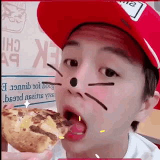 a young boy wearing a red hat is eating a pizza .
