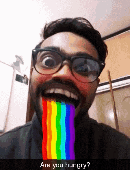 a man wearing glasses has a rainbow coming out of his mouth and the caption says are you hungry