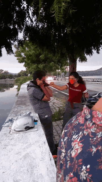 a woman wearing a red shirt that says ' freedom ' on it bumps elbows with a man