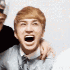 a young man with blonde hair is making a funny face with his mouth wide open .