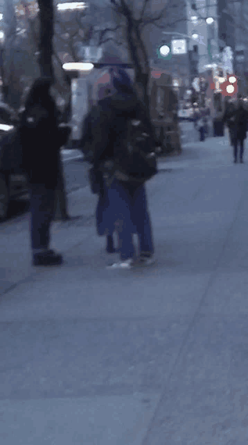 a blurry photo of people walking down a street with a green light in the background