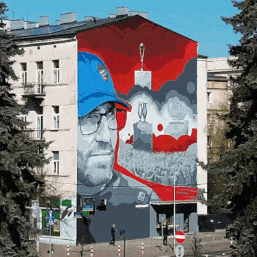 a mural on the side of a building shows a man in a blue hat