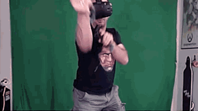 a man is wearing a virtual reality headset while dancing in front of a green screen .