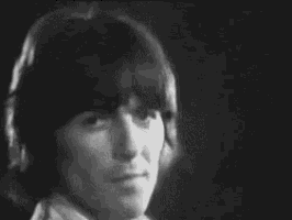 a black and white photo of a young man with long hair and a ponytail .