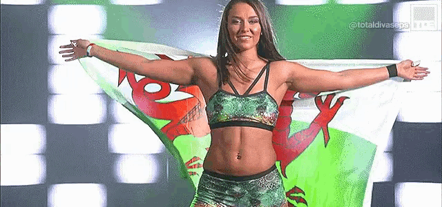 a female wrestler is holding a flag in her arms .