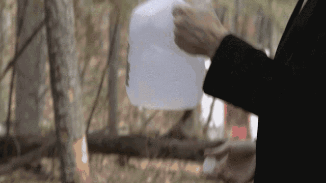 a man in a black suit is holding a white gallon of water