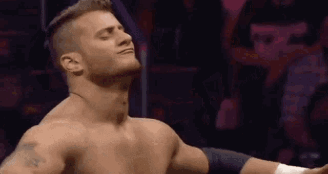 a man without a shirt is standing in a ring with his arms outstretched .