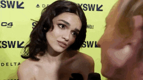 a woman is talking to a man in front of a wall that says ' skw ' on it