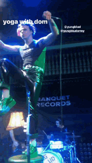 a man is standing on a drum set with banquet records written on the wall behind him