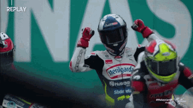 a motorcycle racer wearing a sterilgard helmet celebrates his win