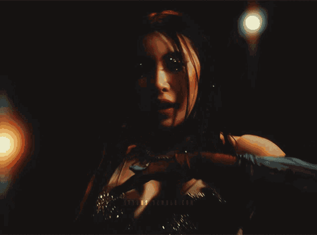 a woman wearing a necklace and gloves is standing in a dark room