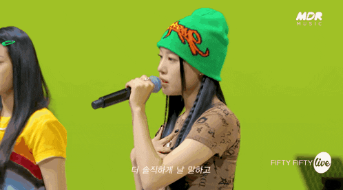 a woman singing into a microphone with the words fifty fifty live on the bottom right