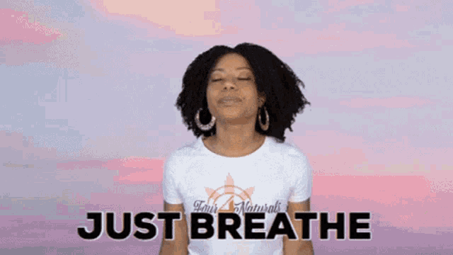 a woman with her eyes closed is wearing a shirt that says just breathe .