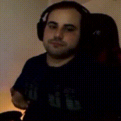 a man wearing headphones is sitting in a chair and holding a controller .