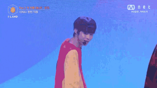a young man is standing on a stage wearing a red and yellow sweater and a microphone .