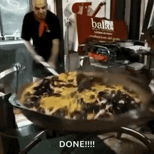 a man is cooking a large pan of food in a kitchen with a sign that says bake in the background .