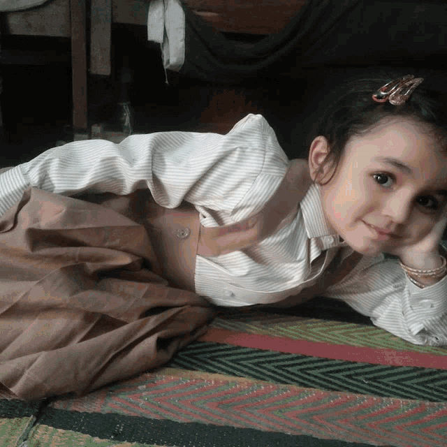 a little girl laying on her stomach with her hand on her face