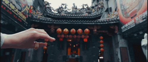 a person 's hand is reaching out towards a building with chinese writing on the side