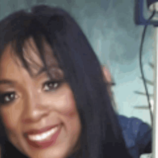 a woman with long black hair and red lipstick is smiling for a picture .